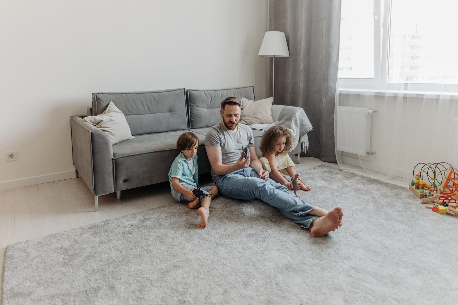 Father and two children enjoy playtime in the living room. Warm family bonding moment captured indoors.